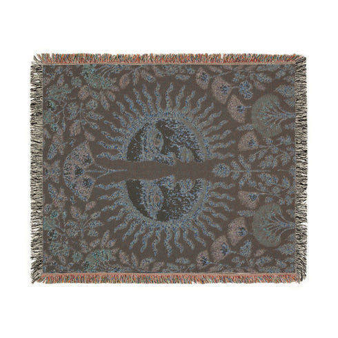 Jacquard-woven cotton blanket featuring twin celestial suns—two serene faces meeting at center—with radiant golden rays on a charcoal ground, bordered by folkloric botanicals and fan blossoms in sage, sky, and garnet. Crafted from 100% soft cotton yarn; the artwork is woven, not printed. Reversible with a color-negative back and finished with a protective 2-inch multicolor fringe. Sizes: 52×37, 50×60, 60×80 for wall, sofa, or queen-bed layering.